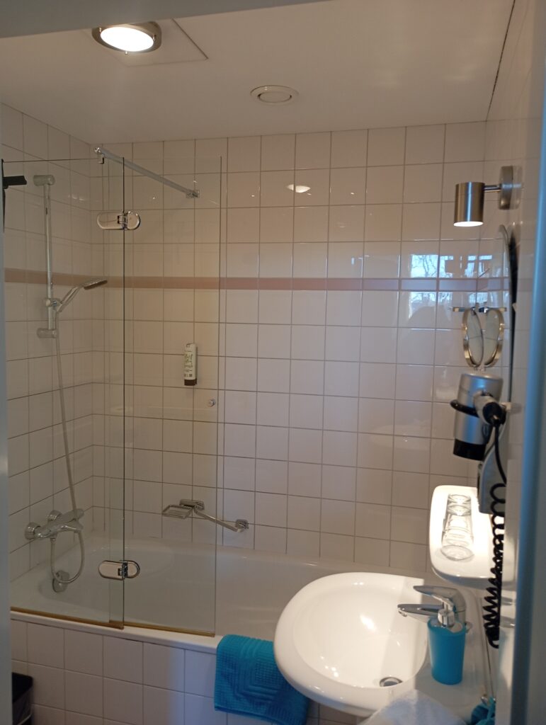 Badezimmer im Studio-Apartment des Hotel Plato Scheveningen by Hofstad Studios mit Badewanne, Dusche und Pflegeprodukten